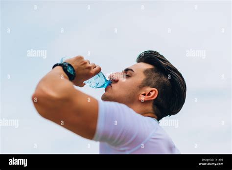Young Exhausted Athlete Drinking Fresh Water To Refresh During A