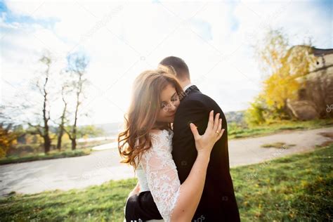 Romantic Newlywed Couple Hugging And Kissing In Autumn Forest At Sunset