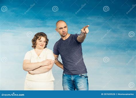 A Plump Red Haired Attractive Woman And A Tall Bald Man On A Blue Background Look To The Side