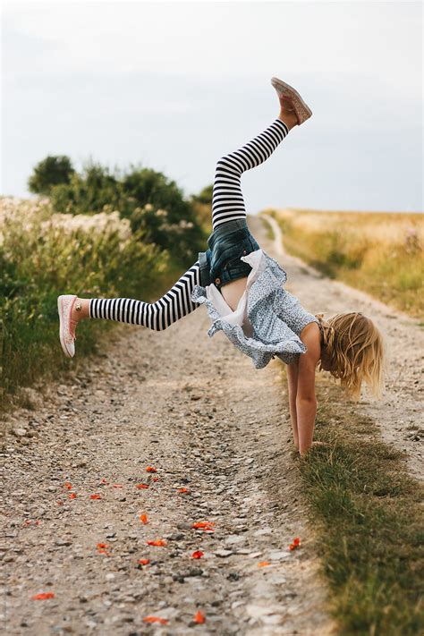 A Little Girl Doing A Handstand On An Unpaved Country Lane By Stocksy