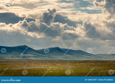 Grass Hills On Horizon In Steppe Under Heavy Clouds Sky During Sunset
