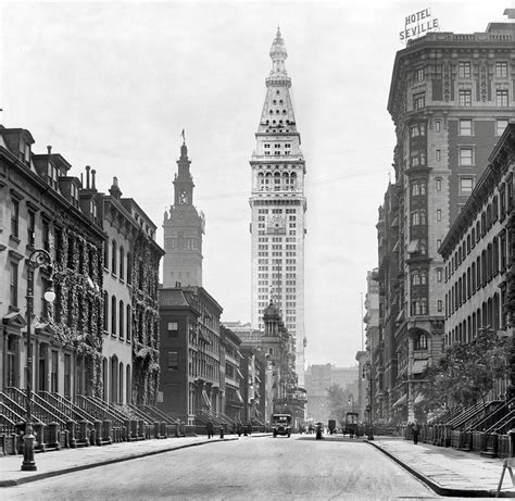 An Old Black And White Photo Of A City Street With Tall Buildings In