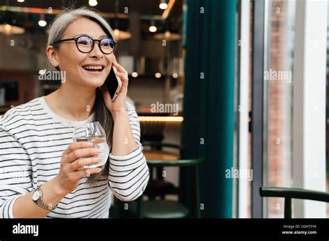 Reife Frau Lächelt Und Redet Am Handy Während Sie Im Café Drinnen Sitzt Stockfotografie Alamy