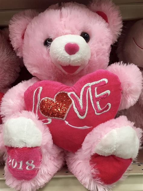 A Pink Teddy Bear Sitting On Top Of A Shelf