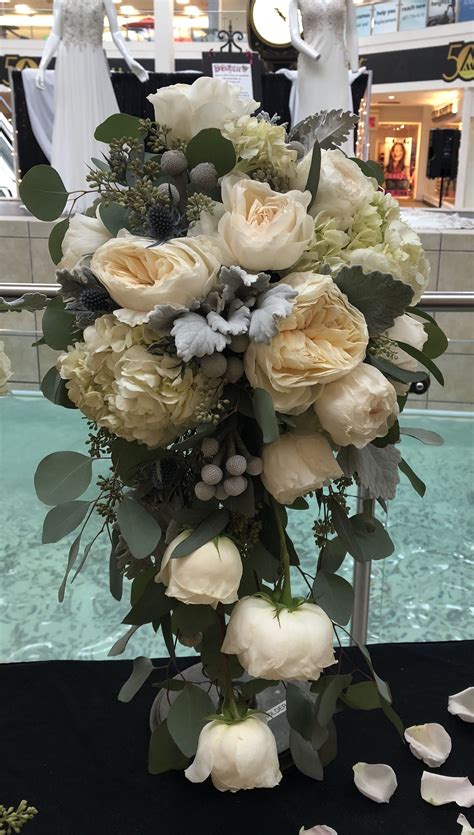 A Bouquet Of White Flowers Sitting On Top Of A Table Next To A Glass Window