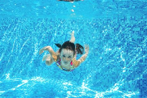 Child Swims In Pool Underwater Happy Active Girl Dives And Has Fun