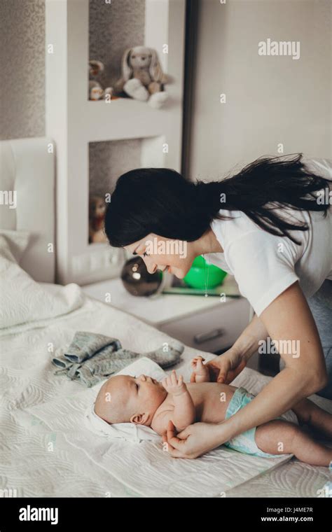 Caucasian Mother Changing Diaper Of Baby Son On Bed Stock Photo Alamy