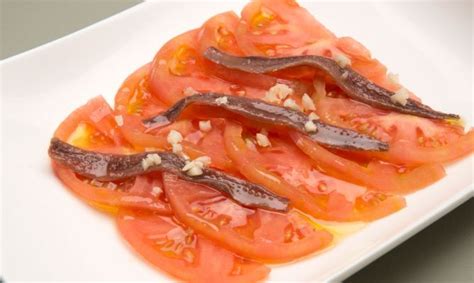 Sliced Tomatoes And Other Vegetables On A White Plate