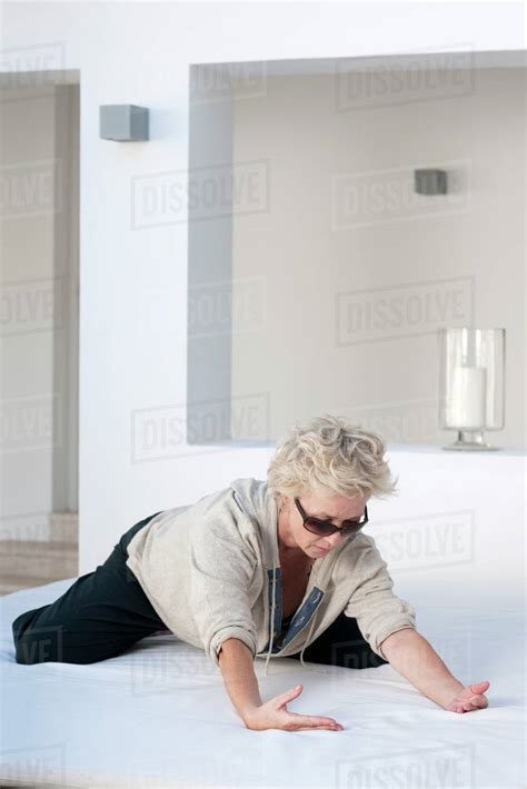 Mature Woman Kneeling On Bed Outdoors Leaning Forward Stock Photo