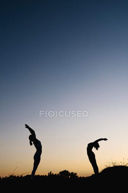 Women Bending Over Backwards While Practicing Yoga Outdoors — Blue Sky