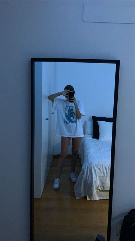 a woman taking a selfie in the mirror with her cell phone while standing next to a bed