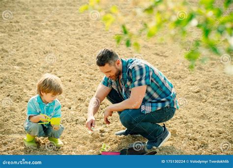 Happy Young Father Planting A Tree While His Little Son Helping Him