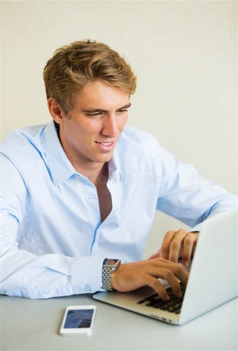 Young Man Working On Laptop Computer Talking On Phone Stock Image