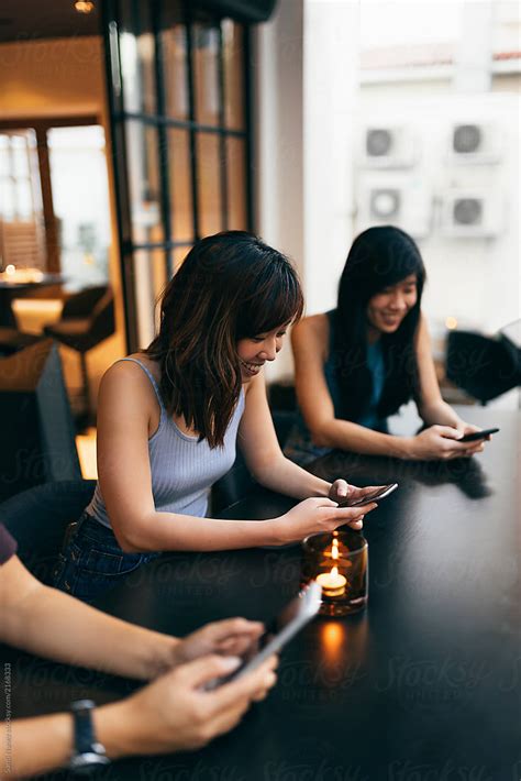 Asian Friends Women Using The Mobile In The Coffee Shop Del Colaborador De Stocksy Santi