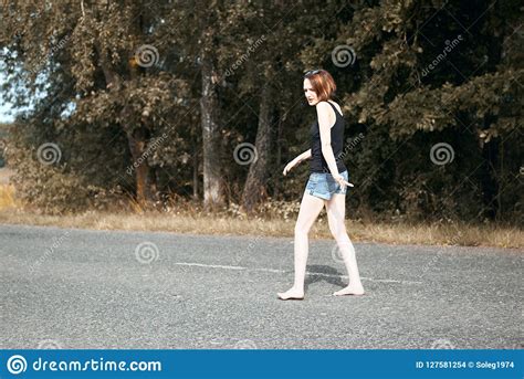 Young Girl Walking Barefoot On The Road The Concept Of Summer And