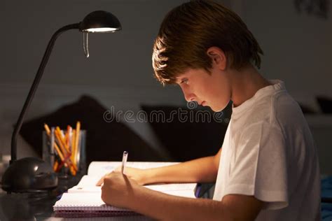 Young Boy Studying At Desk In Bedroom In Evening Stock Image Image Of