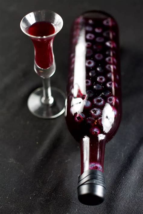 A Wine Bottled Filled With Dark Purple Liqueur And Floating Blueberries