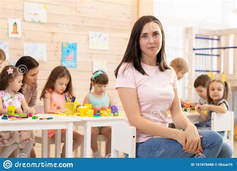 Beautiful Kindergarten Teacher In Classroom With Kids Stock Photo