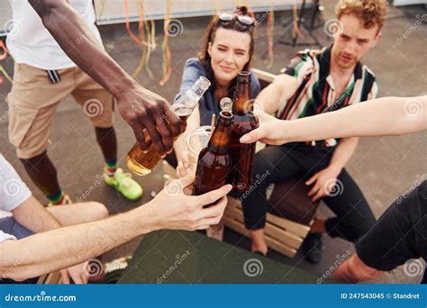 Doing Cheers By Bottles With Beer Group Of Young People In Casual