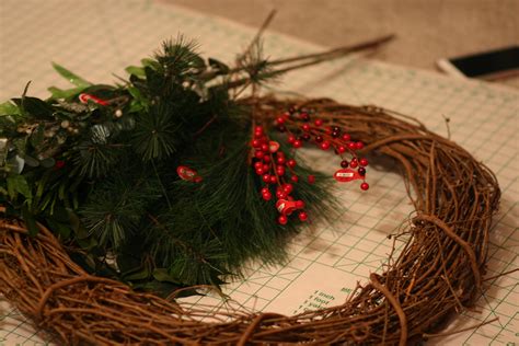 A Wreath With Red Berries And Greenery Is On A Table Next To A Cell Phone