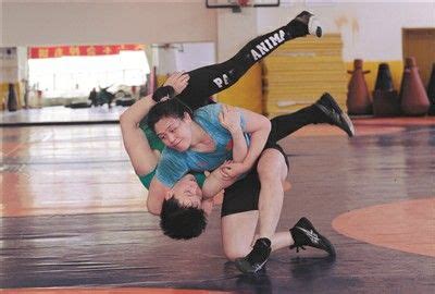 Two People Wrestling In A Gym With One Holding On To The Other S Back