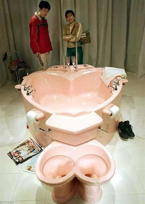 Two People Standing In Front Of A Pink Toilet