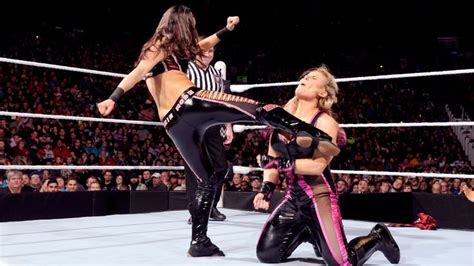 Two Women In Black And Pink Outfits Standing On Top Of A Wrestling Ring