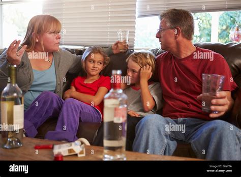Parents Arguing On Sofa With Children Smoking And Drinking Stock Photo