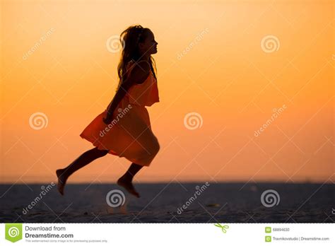 Silhouette Of Adorable Little Girl On White Beach At Sunset Stock Photo