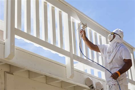 House Painter Wearing Facial Protection Spray Painting A Deck Of A Home