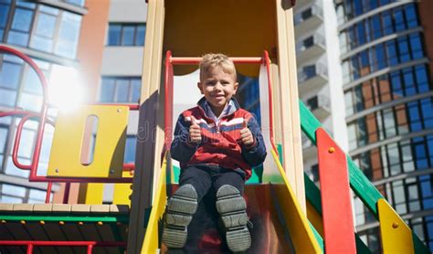 Cute Boy Sitting On Slide At Playground Stock Photo Image Of Young