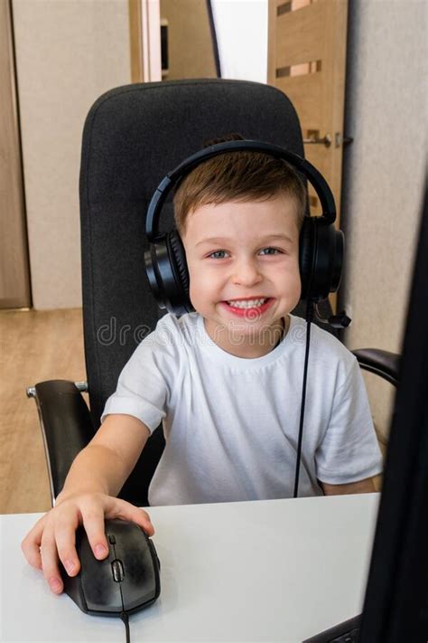 A Caucasian Boy In A White T Shirt And Headphones Is Sitting At A Table