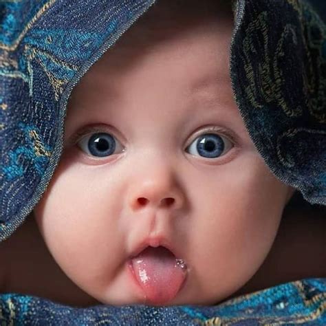 A Close Up Of A Baby Sticking Its Tongue Out And Wearing A Blue Blanket