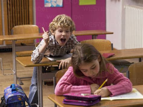 Boy 4 7 Shouting Behind Girl In Class Room Stock Photo
