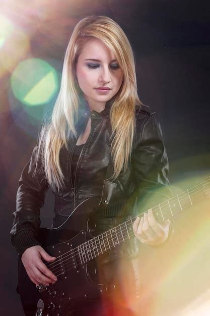 sexy jeune blonde vêtue de cuir noir jouant de la guitare électrique dans un concert photo premium