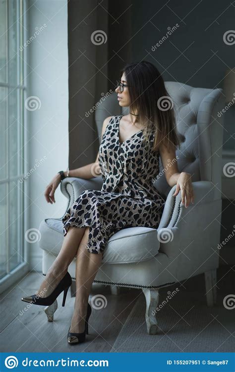 Fashion Portrait Of Young Beautiful Female Model Sitting In Armchair
