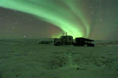 A Truck Is Parked In The Snow Under An Aurora Bore