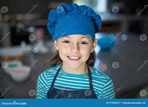 Smiling Girl Wearing An Apron And A Cap In The Kitchen Stock Image