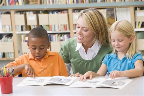 Kindergarten Teacher Helping Students With Reading Skills Stock Photo