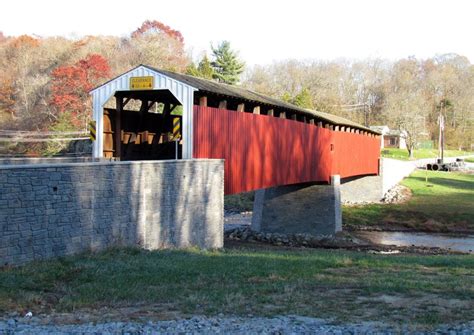 A Red Covered Bridge Over A Small Stream