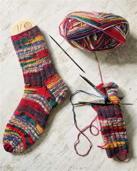 Two Pairs Of Colorful Socks Next To A Ball Of Yarn