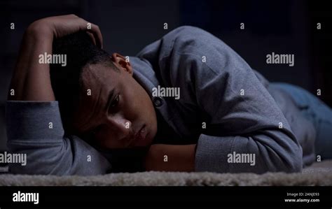 Depressed African American Teenager Suffering Loneliness In Dark Room