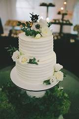 Customised buttercream cakes on instagram: Simple two-tier wedding cake covered in real blossoms and ...