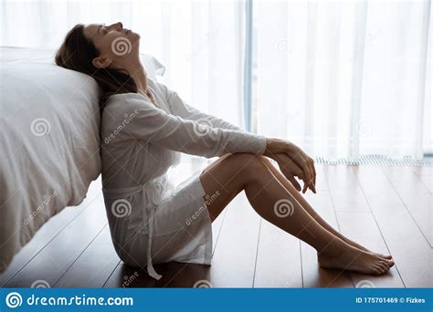 Depressed Young Brunette Woman Sitting On Floor In Bedroom Stock Image