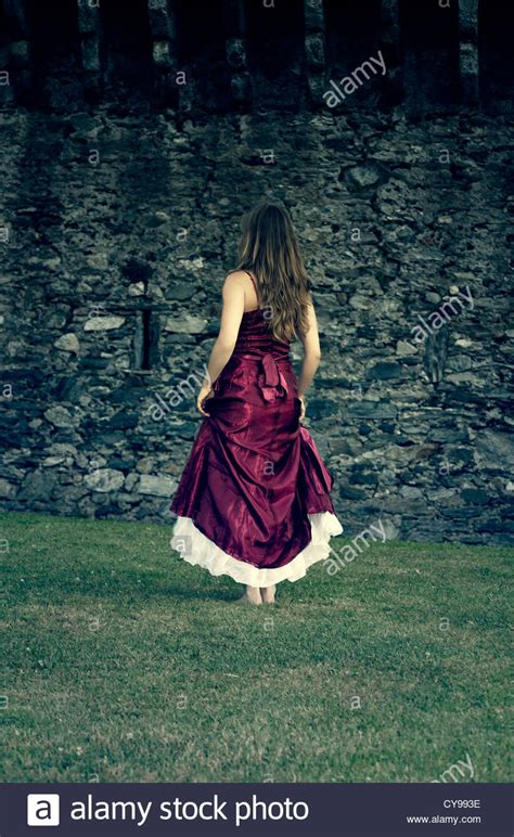 A Woman In A Red Dress Is Running At A Castle Wall Stock Photo