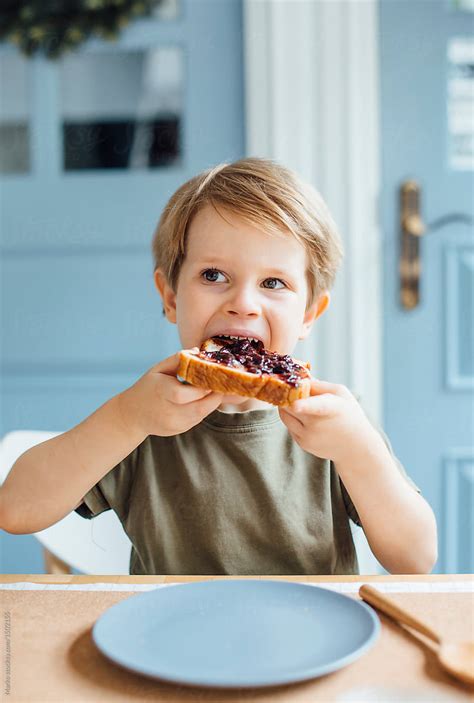 Young Boy Eating Toast With Jam For Breakfast By Stocksy Contributor
