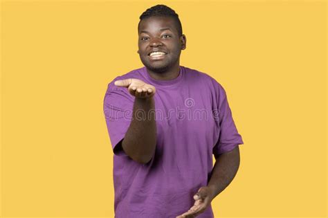 African Man Gesturing Thumbs Up At Camera Over Yellow Background Stock