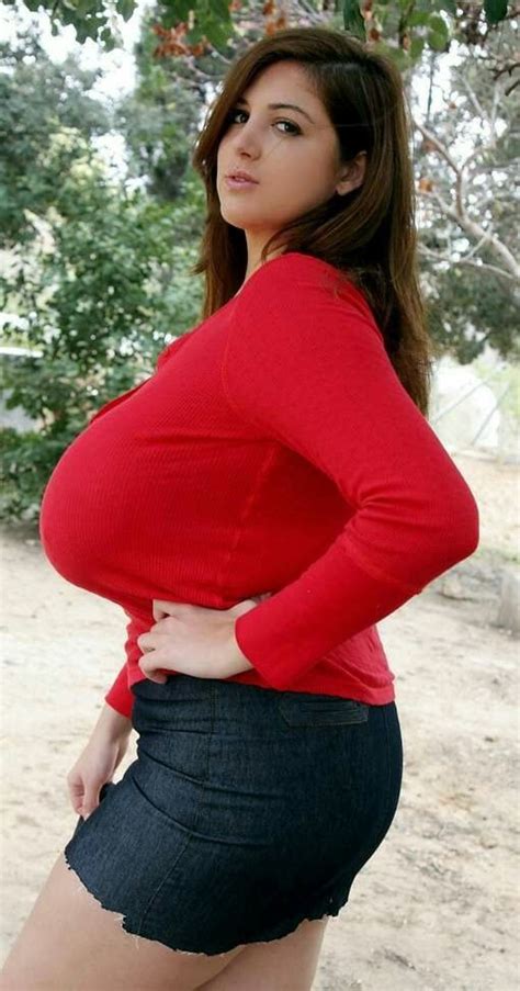 A Woman In A Red Shirt And Black Skirt Posing For The Camera With Her