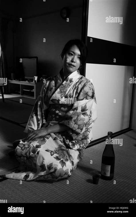 beautiful japanese woman in yukata kimono in a traditional japanese room with a bottle of sake