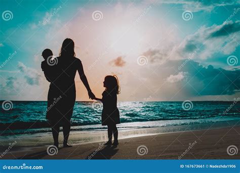 Madre Con Dos Hijos Caminando En La Playa Al Atardecer Imagen De